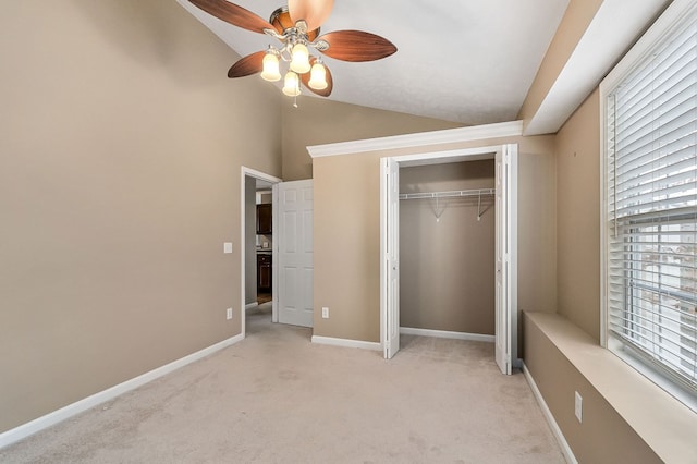 unfurnished bedroom featuring a closet, a ceiling fan, light carpet, vaulted ceiling, and baseboards