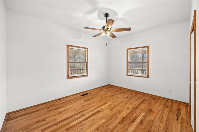 unfurnished room with baseboards, light wood finished floors, visible vents, and a ceiling fan