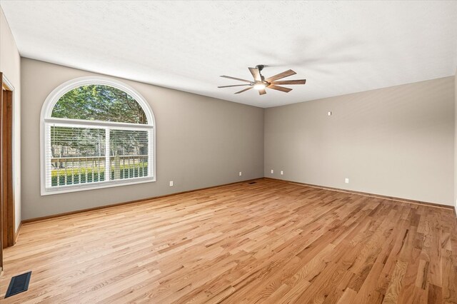 empty room with a textured ceiling, light wood-style flooring, visible vents, and a ceiling fan