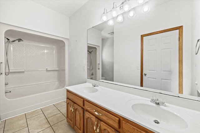 full bath with toilet, double vanity, a sink, and tile patterned floors