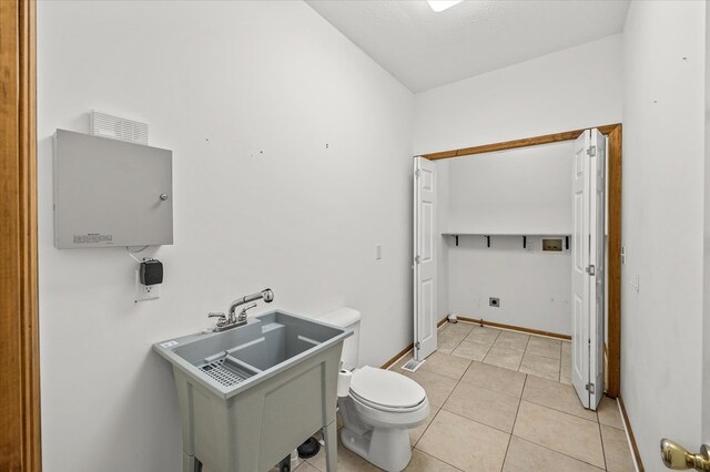 bathroom featuring baseboards, a sink, toilet, and tile patterned floors