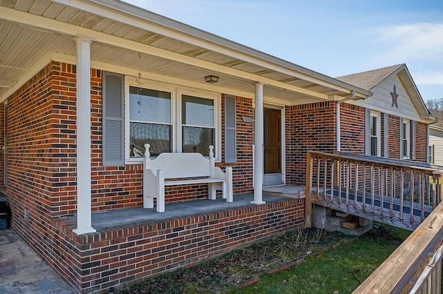 entrance to property featuring a porch and brick siding