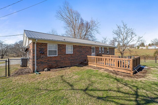 back of house with metal roof, brick siding, a lawn, and a deck