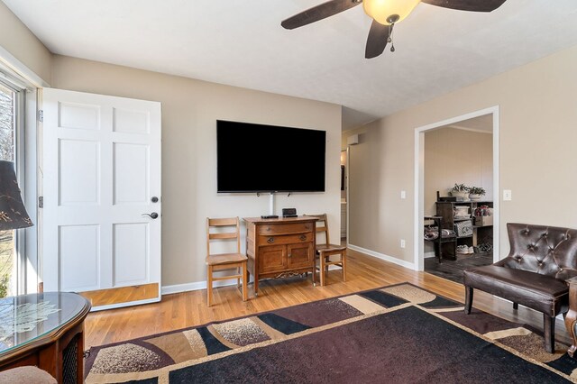 living room with light wood finished floors, baseboards, and a ceiling fan