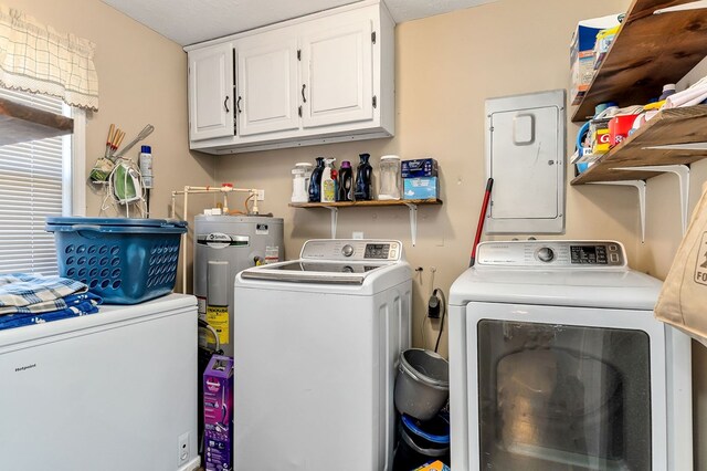 clothes washing area featuring electric water heater, washing machine and clothes dryer, and cabinet space