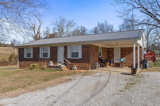 ranch-style house with entry steps, brick siding, and metal roof