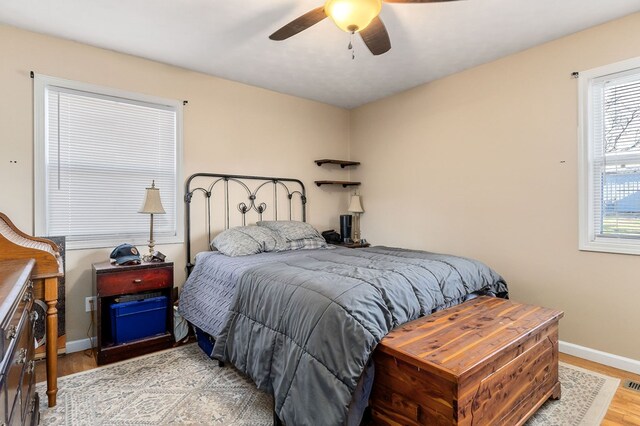 bedroom with light wood-style floors, baseboards, and a ceiling fan