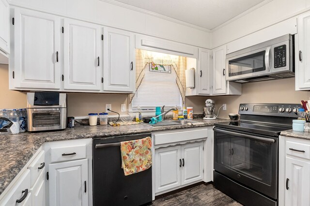 kitchen with black appliances, dark countertops, a sink, and white cabinetry