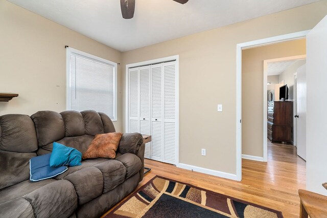 living room with light wood-style flooring, baseboards, and ceiling fan