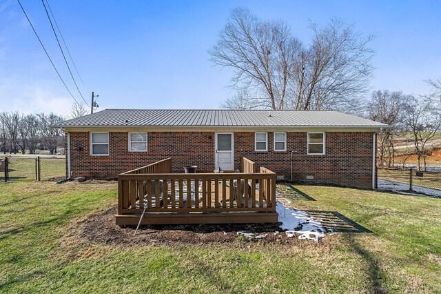 back of property featuring metal roof, brick siding, fence, a lawn, and a wooden deck