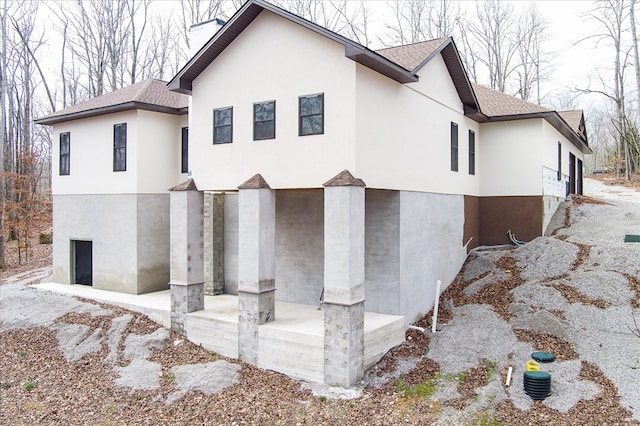 view of home's exterior with a shingled roof and stucco siding