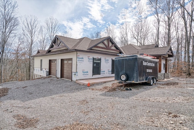 view of front of house with gravel driveway, a garage, and stucco siding