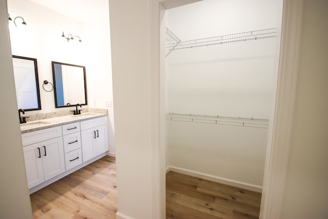 full bath featuring double vanity, a sink, and wood finished floors