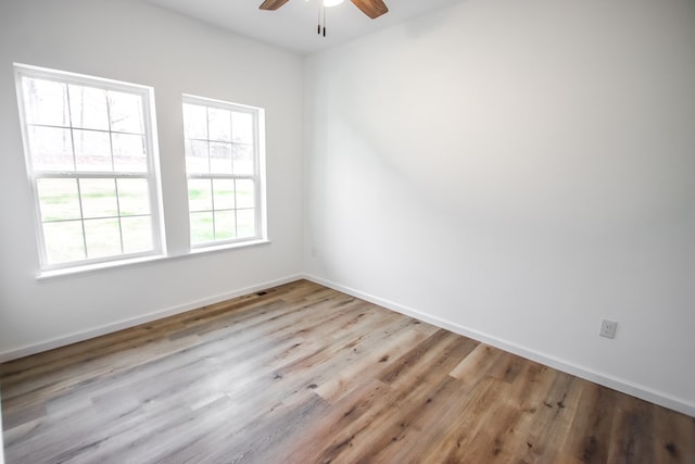 empty room with a ceiling fan, baseboards, and light wood finished floors