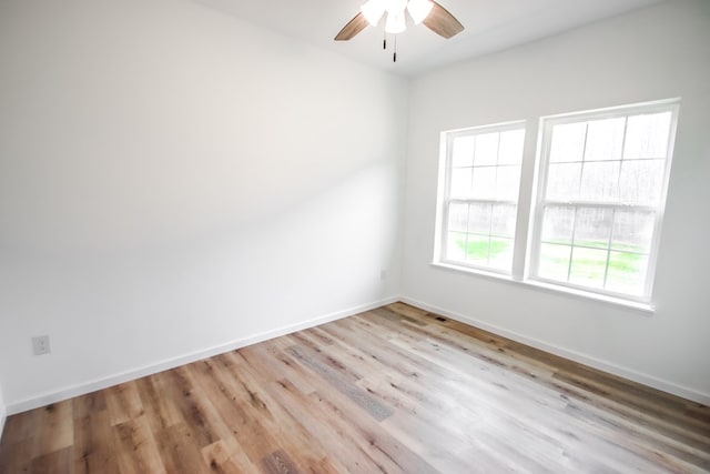 spare room with ceiling fan, light wood-style floors, visible vents, and baseboards