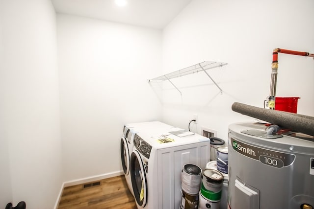 laundry area with laundry area, baseboards, visible vents, wood finished floors, and washing machine and dryer