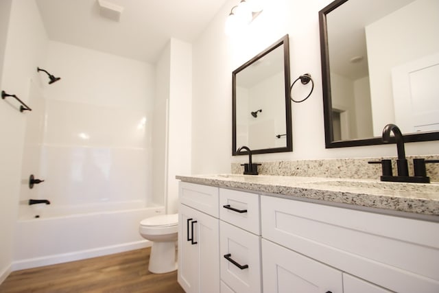 full bathroom with toilet, wood finished floors, a sink, tub / shower combination, and double vanity