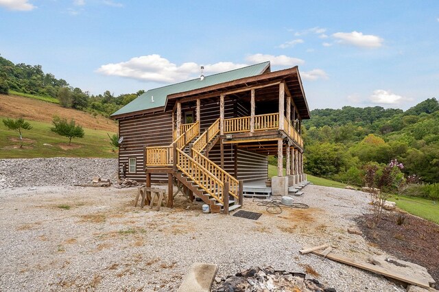 back of house featuring stairs and metal roof