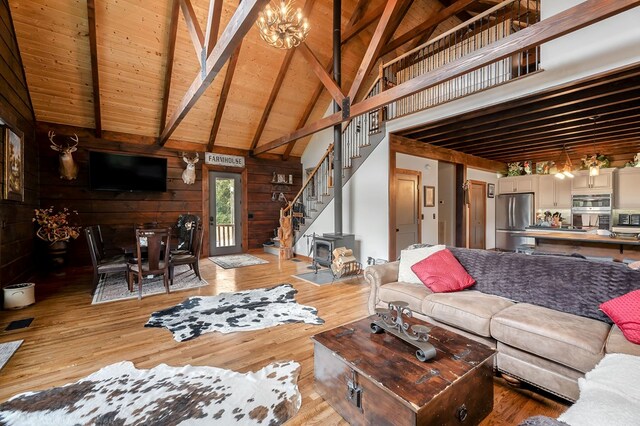 living room with wood ceiling, beamed ceiling, wood walls, light wood-style floors, and high vaulted ceiling