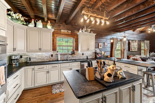 kitchen with dark countertops, open floor plan, a sink, and a peninsula