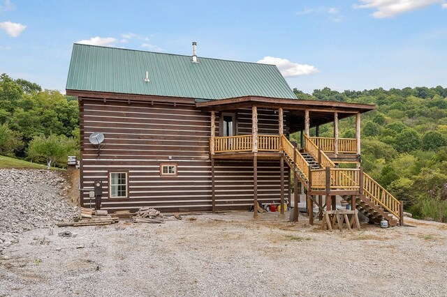 back of house featuring stairs and metal roof