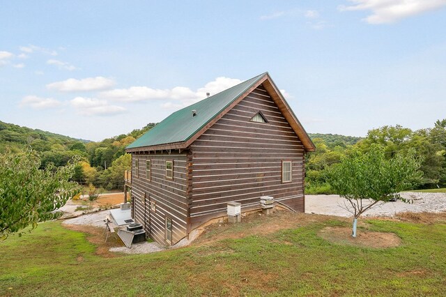 view of property exterior with metal roof and a yard