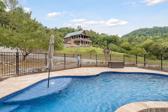 view of swimming pool with a fenced in pool, fence, a forest view, and a patio