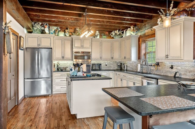 kitchen featuring stainless steel appliances, dark countertops, pendant lighting, and a kitchen breakfast bar