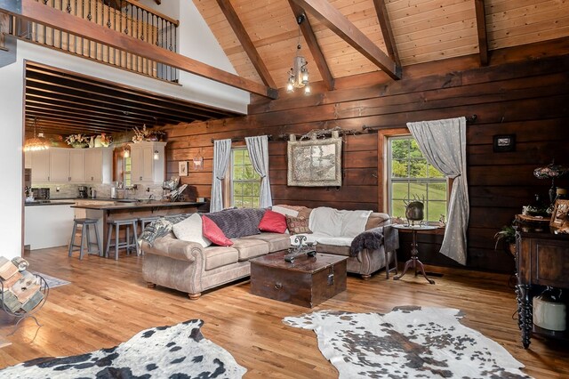 living area with high vaulted ceiling, beamed ceiling, wooden ceiling, and light wood-style flooring