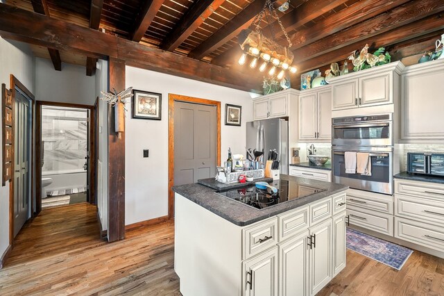 kitchen with beam ceiling, stainless steel appliances, white cabinets, a kitchen island, and wooden ceiling