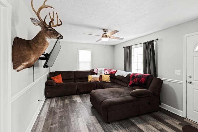 living room with dark wood finished floors, a textured ceiling, baseboards, and ceiling fan