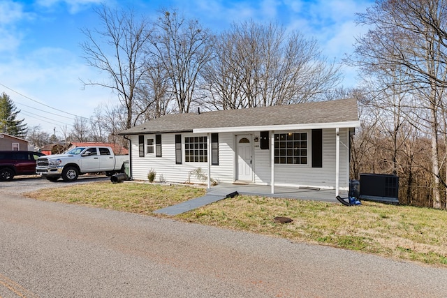 view of front of property with covered porch, a shingled roof, and a front yard