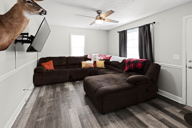 living area featuring a textured ceiling, ceiling fan, dark wood-style flooring, and baseboards