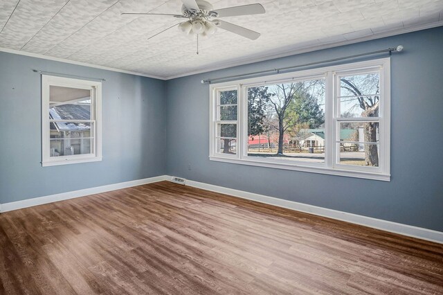 unfurnished room featuring crown molding, wood finished floors, a ceiling fan, and baseboards