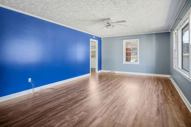 empty room featuring ornamental molding, wood finished floors, visible vents, and baseboards