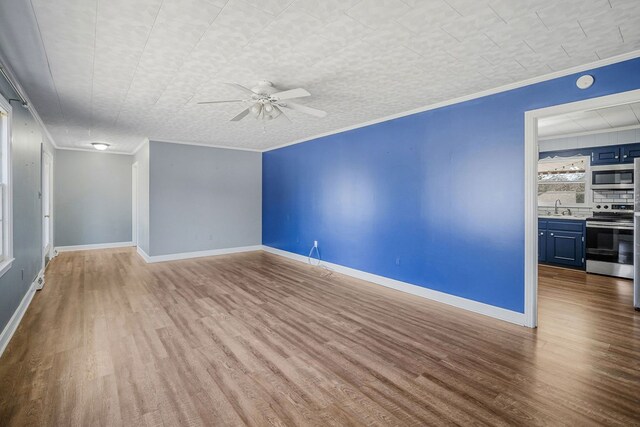 spare room with ornamental molding, a sink, light wood-style flooring, and baseboards