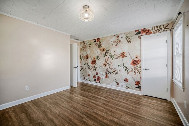 empty room featuring dark wood-style flooring, crown molding, baseboards, and wallpapered walls