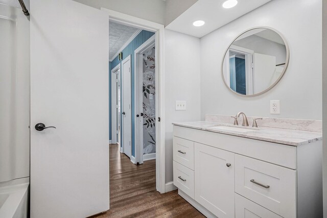 bathroom with recessed lighting, wood finished floors, vanity, and baseboards