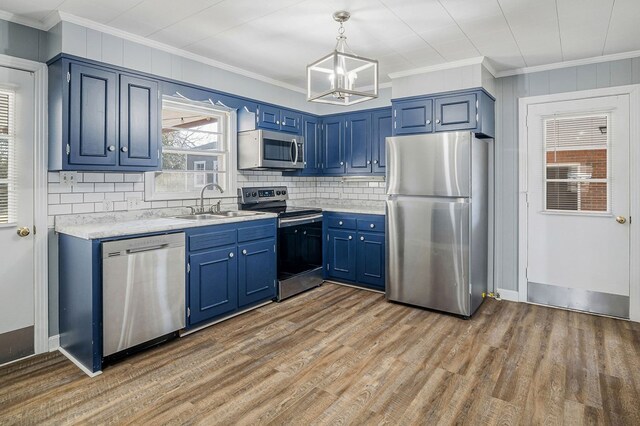 kitchen with blue cabinets, a sink, appliances with stainless steel finishes, light wood-type flooring, and decorative light fixtures