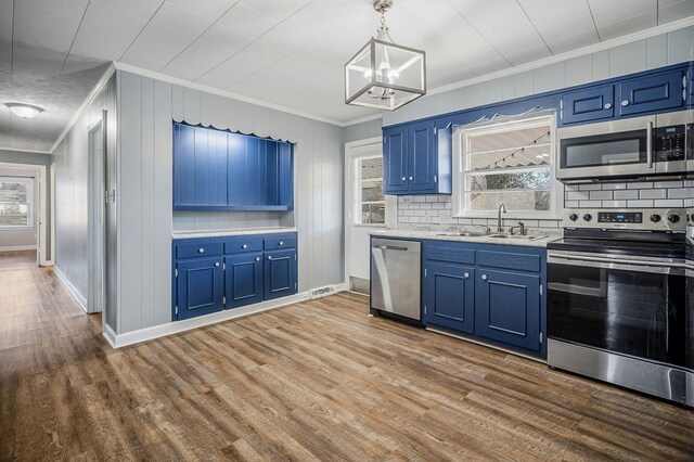 kitchen featuring blue cabinets, stainless steel appliances, light countertops, pendant lighting, and a sink