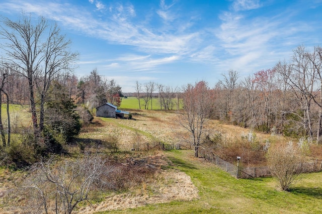 view of yard featuring an outbuilding, fence, and a rural view
