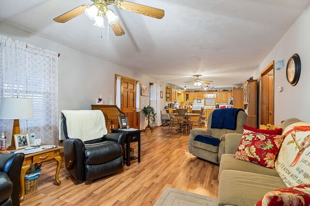 living room featuring a textured ceiling, light wood-style flooring, and a ceiling fan