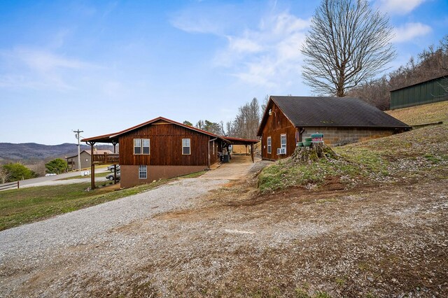 view of side of property featuring gravel driveway and a mountain view