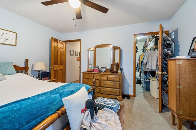 bedroom featuring light carpet, baseboards, a ceiling fan, a spacious closet, and a closet