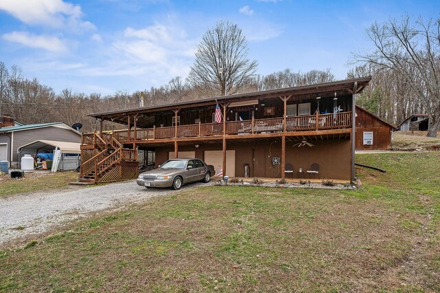 view of front of home featuring a deck, a garage, driveway, a front lawn, and stairs