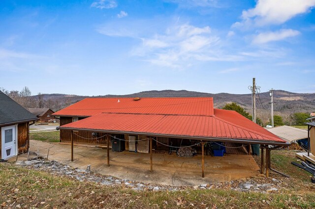 rear view of property with an outbuilding, metal roof, cooling unit, a mountain view, and an exterior structure