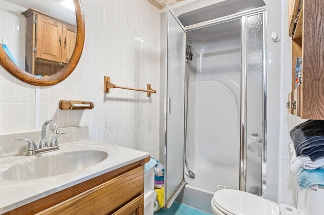 full bathroom featuring toilet, vanity, tile walls, decorative backsplash, and a stall shower