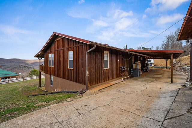 view of side of property with driveway, an attached carport, central AC unit, and a mountain view