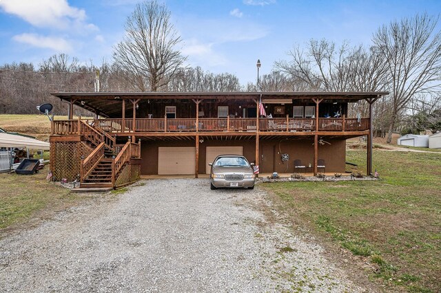 rustic home featuring gravel driveway, a deck, a garage, a front lawn, and stairs