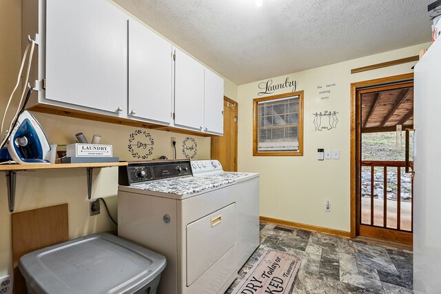 laundry room with cabinet space, baseboards, stone finish floor, a textured ceiling, and separate washer and dryer